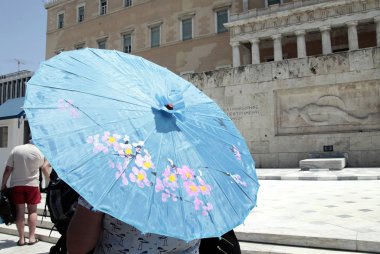 Atina'da sıcak hava dalgası sırasında Atina'nın merkezindeki sokakta yürüyen insanlar, 11 Temmuz 2017