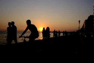 Yayalar sıcak bir yaz gün batımı sırasında sahil şeridinde yürümek, Ağustos'ta Selanik kuzey Yunanistan kentinde 22, 2019.