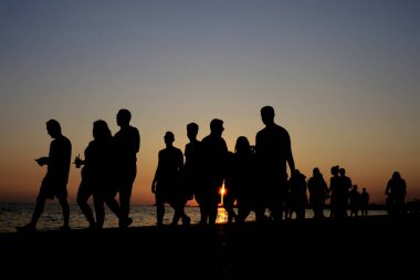 Yayalar sıcak bir yaz gün batımı sırasında sahil şeridinde yürümek, Ağustos'ta Selanik kuzey Yunanistan kentinde 22, 2019.