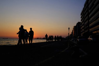 Yayalar sıcak bir yaz gün batımı sırasında sahil şeridinde yürümek, Ağustos'ta Selanik kuzey Yunanistan kentinde 22, 2019.