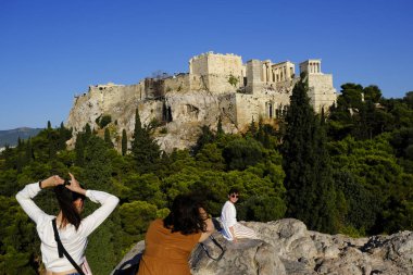 Turistler Atina'daki anıttan fotoğraf çekerken Akropolis tepesini ziyaret ettiler, Yunanistan 9 Ağustos 2019