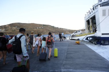 Turist sezonu Yunanistan için zirveye ulaşırken turistler Serifos limanında yolcu gemisinden karaya, Serifos Ağustos'ta 19, 2019