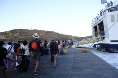 Turist sezonu Yunanistan için zirveye ulaşırken turistler Serifos limanında yolcu gemisinden karaya, Serifos Ağustos'ta 19, 2019