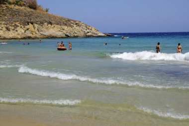 İnsanlar denizde banyo ve 13 Ağustos'ta Serifos Yunan Adası'nda Psili Ammos sahilde oyun oynarken
