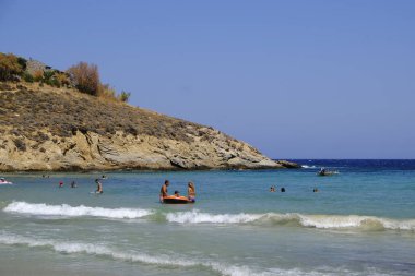 İnsanlar denizde banyo ve 13 Ağustos'ta Serifos Yunan Adası'nda Psili Ammos sahilde oyun oynarken