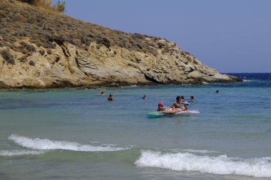 İnsanlar denizde banyo ve 13 Ağustos'ta Serifos Yunan Adası'nda Psili Ammos sahilde oyun oynarken