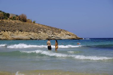 İnsanlar denizde banyo ve 13 Ağustos'ta Serifos Yunan Adası'nda Psili Ammos sahilde oyun oynarken