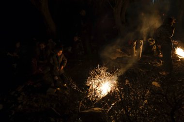 Göçmenler 3 Mart 2020 'de Yunanistan' ın Skala Sikamineas köyü yakınlarında bir şenlik ateşinin yanında ısındılar..