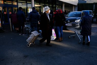 Brüksel, Belçika. 18 Mart 2020. Bir adam alışverişini Belçika hükümeti koronavirüsü uygulamadan önce süpermarketin dışına taşır..