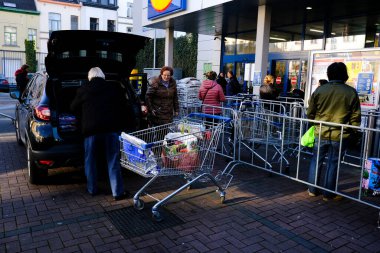 Brüksel, Belçika. 18 Mart 2020. Belçika hükümeti Coronavirus 'u kapatmadan önce bir adam alışverişini süpermarketin dışında bir arabaya yüklüyor..