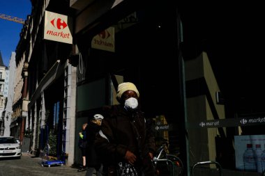 Brüksel, Belçika. 18 Mart 2020. Koronavirüs salgını sonrasında koruyucu yüz maskeleri takan insanlar Brüksel 'in tarihi merkezine doğru yol alıyorlar..