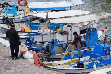 LESBOS Adası, GREECE - 4 Mart 2020. Bir balıkçı prens limanda ağ örüyor. Yunan adaları balık yakalamak için kullanılan geleneksel tekneleriyle ünlüdür