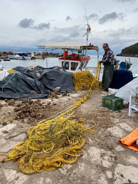 LESBOS ISLAND, GREECE - March 5, 2020. A Fisherman prpeares nets in port. Greek islands are famous for traditional boats used to catch fish — Stock Image Lesbos Island Greece March 2020 Fisherman Prpeares Nets Port Greek Stock Photo