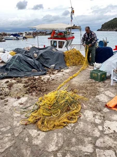 LESBOS ISLAND, GREECE - March 5, 2020. A Fisherman prpeares nets in port. Greek islands are famous for traditional boats used to catch fish — Stock Image Lesbos Island Greece March 2020 Fisherman Prpeares Nets Port Greek Stock Photo