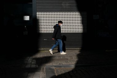 Belçika 24 Mart 2020 'de Brüksel, Belçika' da Coronavirus hastalığının yayılmasını yavaşlatmak için şehir merkezinde yürüyen koruyucu yüz maskesi takan bir yaya görülüyor.
