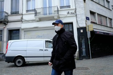 Belçika 19 Mart 2020 'de Brüksel, Belçika' da koronavirüs hastalığının yayılmasını yavaşlatmak için şehir merkezinde yürüyen koruyucu yüz maskesi takan bir yaya görülüyor.
