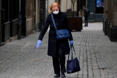 Belçika 19 Mart 2020 'de Brüksel, Belçika' da koronavirüs hastalığının yayılmasını yavaşlatmak için şehir merkezinde yürüyen koruyucu yüz maskesi takan bir yaya görülüyor.