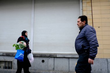  Belçika 'nın 19 Mart 2020' de Brüksel, Belçika 'da Coronavirus hastalığının yayılmasını yavaşlatmak için tecrit uygulaması sonrasında, bir tüketici alışveriş çantasıyla Brüksel şehir merkezinde yürüyor