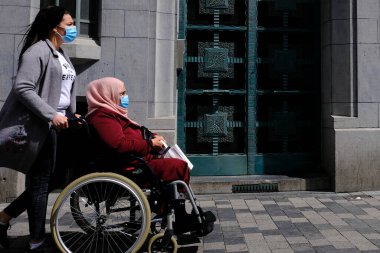 30 Nisan 2020 'de Brüksel, Belçika' da tekerlekli sandalyede oturan bir kız ve annesi..