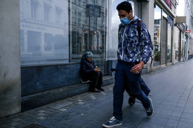 Belçika 'nın 30 Nisan 2020' de Brüksel, Belçika 'da Coronavirus hastalığının yayılmasını yavaşlatmak için şehir merkezinde yürüyen koruyucu maskeli bir yaya görülüyor..