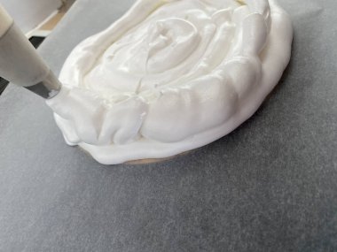 Kadın eli çırpılmış kremayı kağıt üzerinde sıkıyor.. 