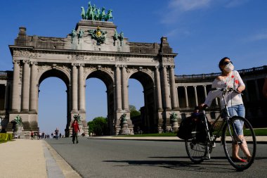 24 Nisan 2020 'de Brüksel, Belçika' da güneşli bir günde, yüz maskesi takan bir yaya Parc du Cinquantenaire 'de yürür..