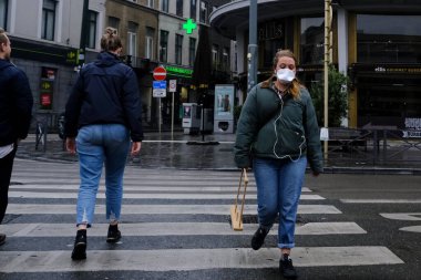 A pedestrian wearing a protective face mask walks in city center after Belgium imposed a lockdown to slow down the spread of the coronavirus disease in Brussels, Belgium on April 28, 2020. clipart