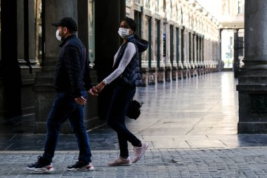Belçika 27 Nisan 2020 'de Brüksel, Belçika' da Coronavirus hastalığının yayılmasını yavaşlatmak için şehir merkezinde yürüyen koruyucu yüz maskesi takan bir yaya görülüyor..