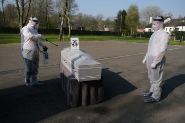 Eldiven ve koruyucu yüz maskesi takan morg çalışanları 9 Nisan 2020 'de şirketin Charleroi, Belçika' daki morgunda COVID-19 kurbanının tabutunu dezenfekte ediyor..