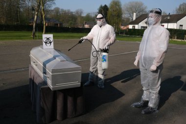Eldiven ve koruyucu yüz maskesi takan morg çalışanları 9 Nisan 2020 'de şirketin Charleroi, Belçika' daki morgunda COVID-19 kurbanının tabutunu dezenfekte ediyor..