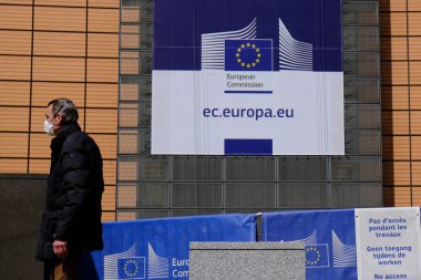 15 Nisan 2020 'de Brüksel, Belçika' daki Avrupa Komisyonu genel merkezinin önünde koruyucu maske takan bir yaya yürüyor..