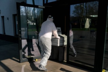 Pompes Funebres Fontaine 'in cenaze levazımatçıları koruyucu giysiler içinde Belçika, Gilly' deki bir COVID 19 kurbanının tabutunu taşıyorlar. 9, 2020