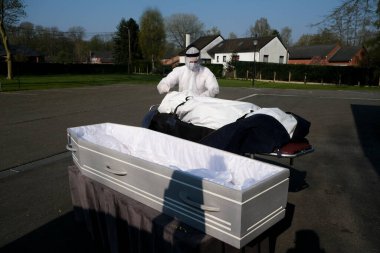Mortuary workers put the body of a victim of the coronavirus disease (COVID-19) inside a coffin at the Fontaine funeral home during a partial lockdown to prevent the spread of coronavirus in Charleroi, Belgium, on April 9 , 2020. clipart