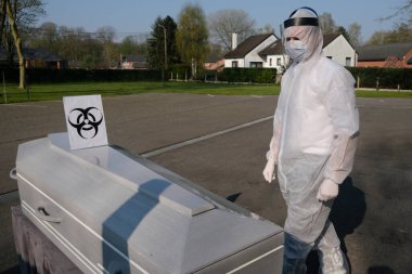 9 Nisan 2020 'de Belçika' nın Charleroi kentindeki bir cenaze evinde Coronavirus hastalığı kurbanının cesedinin yanında duran bir morg çalışanı.