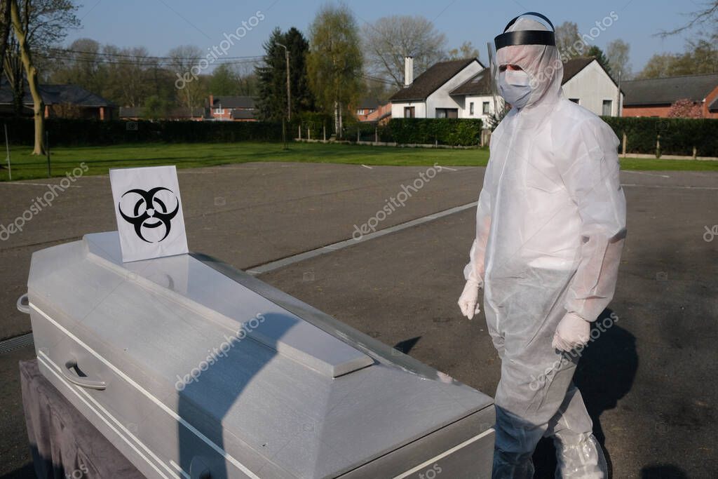 A Mortuary worker stands next to the body of a victim of the coronavirus disease inside a coffin at funeral home  in Charleroi, Belgium, on April 9, 2020