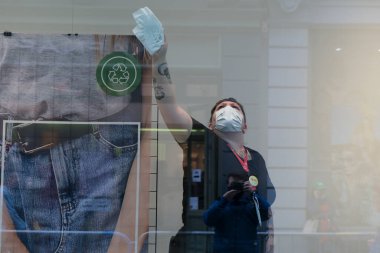 Bir giyim mağazasının çalışanı, 4 Haziran 2020 'de Brüksel, Belçika' da açılmadan önce bir alışveriş penceresini temizler..