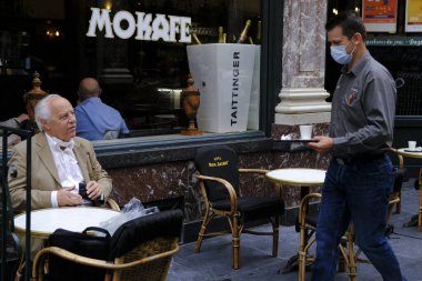 Koruyucu maske takan bir garson, Belçika 'nın Brüksel kentinde meydana gelen koronavirüs hastalığının ortasında haftalar süren tecrit kısıtlamaları sonrasında restoranlar ve barlar olarak müşteriye hizmet veriyor. 8, 2020.