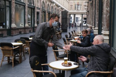 Koruyucu maske takan bir garson, Belçika 'nın Brüksel kentinde meydana gelen koronavirüs hastalığının ortasında haftalar süren tecrit kısıtlamaları sonrasında restoranlar ve barlar olarak müşteriye hizmet veriyor. 8, 2020.