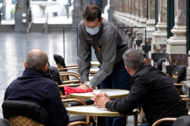 Koruyucu maske takan bir garson, Belçika 'nın Brüksel kentinde meydana gelen koronavirüs hastalığının ortasında haftalar süren tecrit kısıtlamaları sonrasında restoranlar ve barlar olarak müşteriye hizmet veriyor. 8, 2020.
