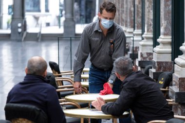 Koruyucu maske takan bir garson, Belçika 'nın Brüksel kentinde meydana gelen koronavirüs hastalığının ortasında haftalar süren tecrit kısıtlamaları sonrasında restoranlar ve barlar olarak müşteriye hizmet veriyor. 8, 2020.