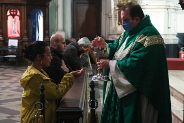 A priest wearing a face mask, gives the communion to a worshiper during the first Mass since the start of the COVID-19 Coronavirus pandemic at Catholic church in Brussels, Belgium on Jun. 8, 2020. clipart
