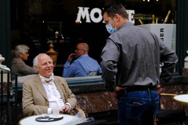 Koruyucu maske takan bir garson, Belçika 'nın Brüksel kentinde meydana gelen koronavirüs hastalığının ortasında haftalar süren tecrit kısıtlamaları sonrasında restoranlar ve barlar olarak müşteriye hizmet veriyor. 8, 2020.