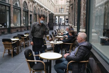 Koruyucu maske takan bir garson, Belçika 'nın Brüksel kentinde meydana gelen koronavirüs hastalığının ortasında haftalar süren tecrit kısıtlamaları sonrasında restoranlar ve barlar olarak müşteriye hizmet veriyor. 8, 2020.