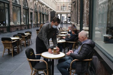 Koruyucu maske takan bir garson, Belçika 'nın Brüksel kentinde meydana gelen koronavirüs hastalığının ortasında haftalar süren tecrit kısıtlamaları sonrasında restoranlar ve barlar olarak müşteriye hizmet veriyor. 8, 2020.