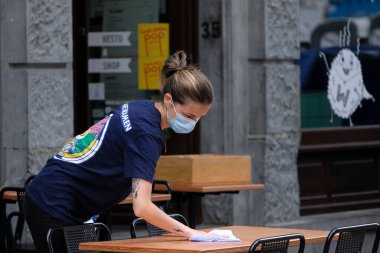 Belçika 'da 4 Haziran 2020' de meydana gelen koronavirüs hastalığı (COVID-19) salgını sonrasında ülke tecrit kısıtlamalarını gevşetmeye başladığında, bir çalışan Brüksel 'in merkezinde bir restoranın terasını hazırlıyor.