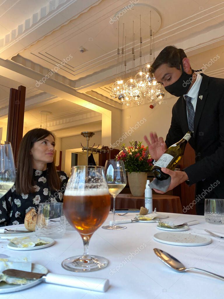 Un empleado en el restaurante, con una máscara protectora, sirve a los