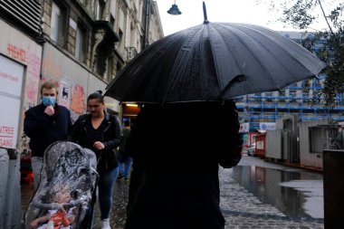Belçika 'da 17 Haziran 2020' de meydana gelen yaz fırtınası sırasında insanlar Brüksel 'in merkezinde yürüyorlar..