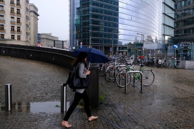 Belçika 'da 17 Haziran 2020' de meydana gelen yaz fırtınası sırasında insanlar Brüksel 'in merkezinde yürüyorlar..