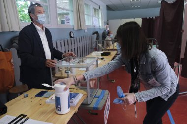 A municipal worker sanitizes the polling booth at a polling station, during the second round of the French Municipal elections in Lille, France on June 28, 2020. clipart