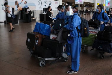 Koronavirüsün yayılmasını önlemek için maske takan yolcular, 24 Temmuz 2020 'de Brüksel, Belçika' daki Zaventem uluslararası havaalanındaki panoya bakın.